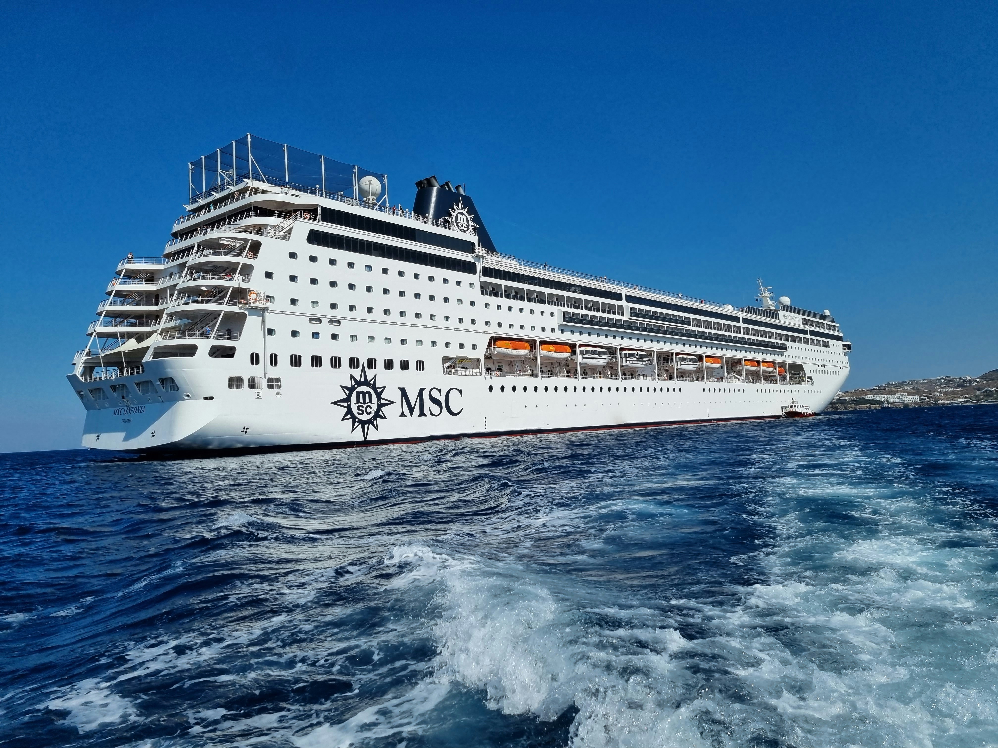 A cruise ship sailing across open ocean at sunset